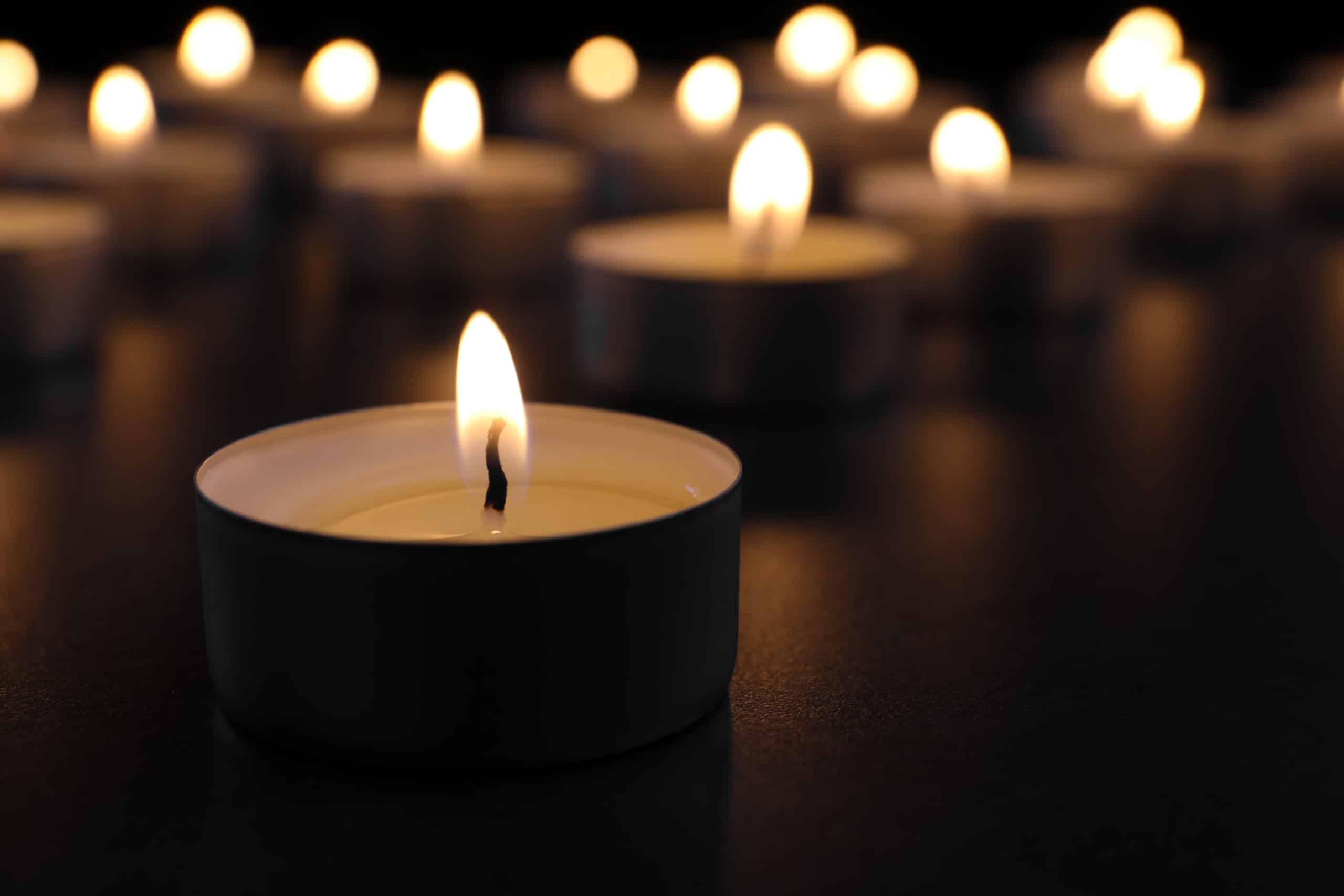 Burning candle on table in darkness