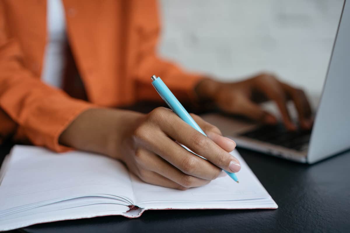 A female hand with a pen/pencil is writing on an exercise book