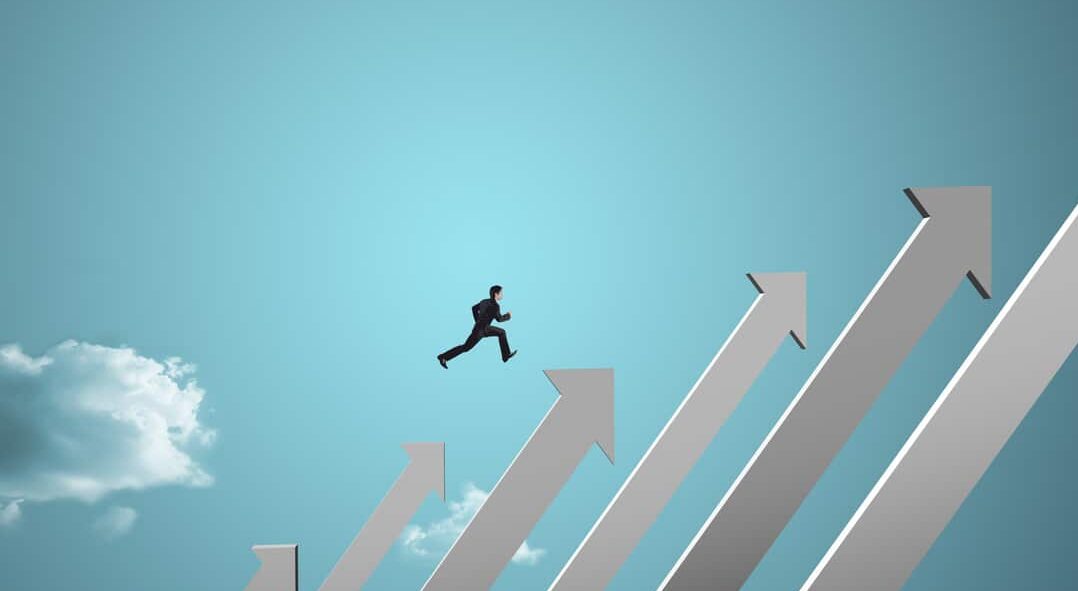 businessman jumping on growing chart with sky background