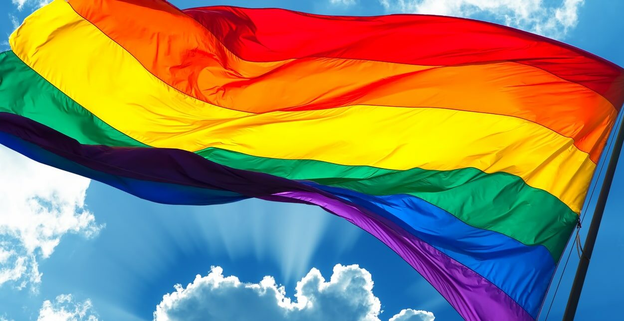 rainbow flag on cloudy sky background