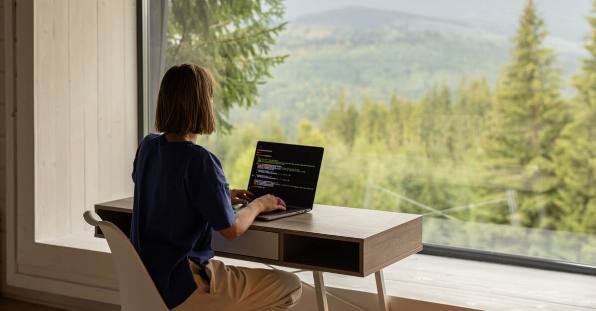 woman works on laptop remotely in house on nature