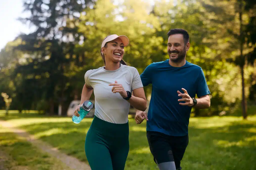 cheerful athletic couple jogging through the park.