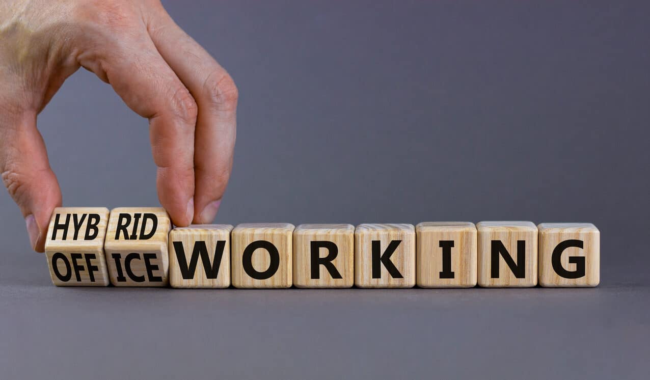 hybrid or office working symbol. businessman turns cubes and changes words 'office working' to 'hybrid working'. beautiful grey background. business, hybrid or office working concept, copy space.