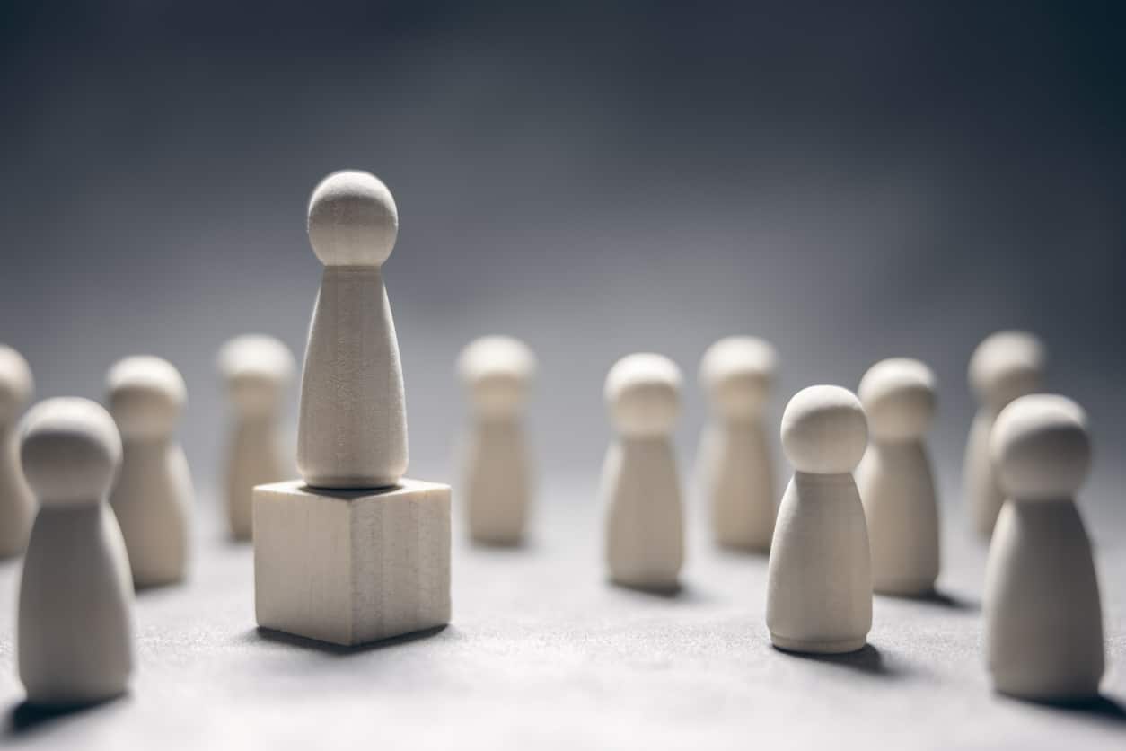leadership wooden business team with one person standing out from the crowd on podium