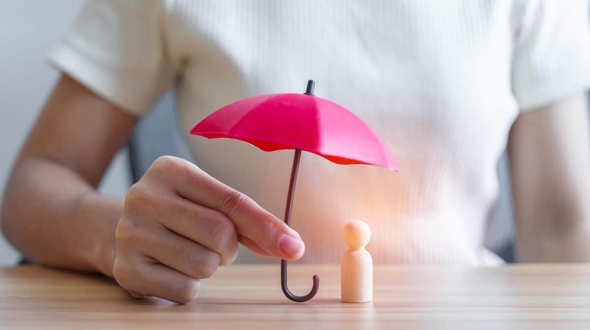 hand holding red umbrella and cover wood man. people protect, life insurance, health and leadership concepts